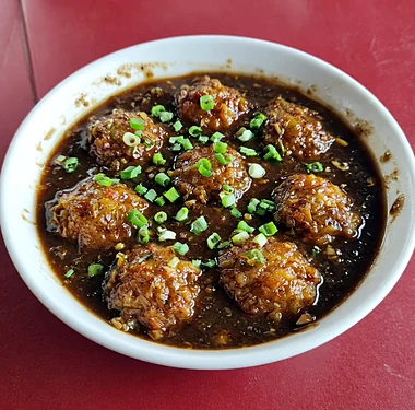 Veg Manchurian balls in a dark soy garlic gravy with spring onion